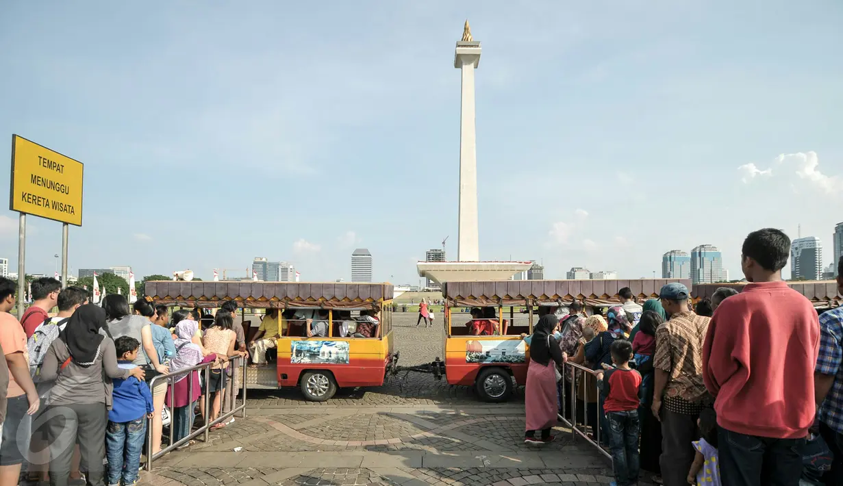 Sejumlah warga antri untuk menaiki kereta wisata di halaman Monumen Nasional, Jakarta, Kamis (7/7). Libur kedua Lebaran dimanfaatkan warga untuk bekunjung ke lokasi wisata bersama keluarga. (Liputan6.com/Yoppy Renato)