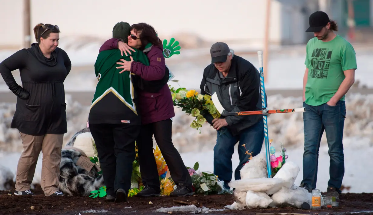 Keluarga dan kerabat menaruh bunga di lokasi kecelakaan bus yang membawa tim hoki es Humboldt Broncos di Provinsi Saskatchewan, Kanada (9/4). Sebanyak 14 orang tewas dalam kecelakaan tersebut. (Jonathan Hayward/The Canadian Press via AP)