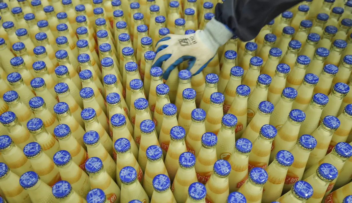 Pekerja memeriksa botol-botol susu kedelai di sebuah pabrik di Nanning, Guangxi, China, Selasa (12/3). Pabrikan asal China menghadapi tekanan penjualan di dalam dan luar negeri. (STR/AFP)