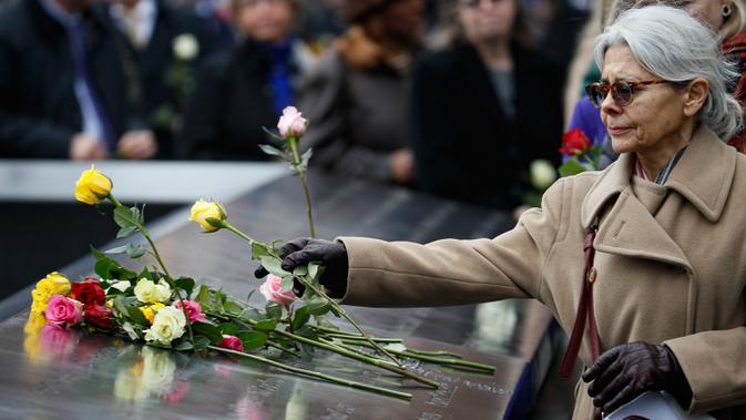 Orang-orang menaruh bunga mawar di atas nama korban pengeboman World Trade Center 1993 pada upacara peringatan 