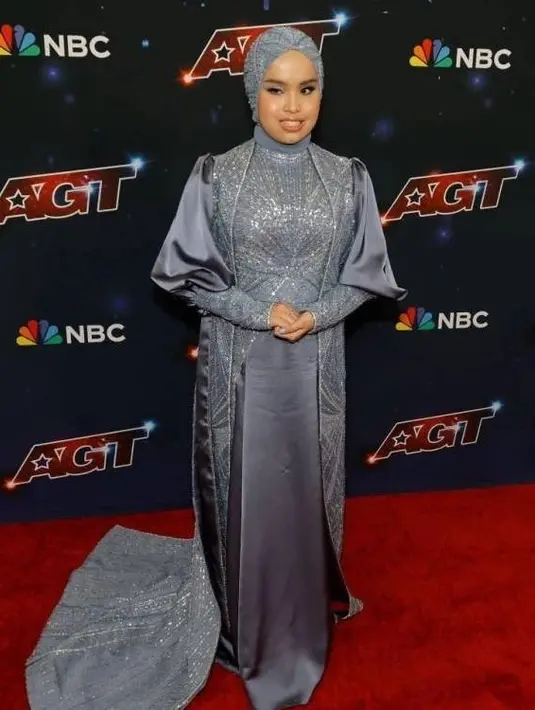 Di final AGT, Putri kembali mengenakan gaun rancangan Tiffany Liem. Kali ini, ia memilih gaun berwarna kebiruan yang memiliki ekor panjang hingga menyapu lantai. [@portalpageanti]