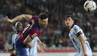 Penyerang Barcelona #09 Robert Lewandowski mengincar bola di samping bek Real Sociedad #24 Robin Le Normand pada laga jornada 35 La Liga 2023/2024 yang dihelat di Estadio Olimpico Lluis Companys, Selasa (14/5/2024) dini hari WIB. (LLUIS GENE / AFP)