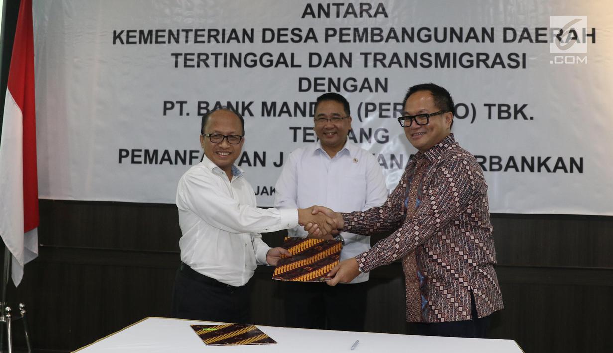 Mendes PDTT Eko Putro Sandjojo (tengah) menyaksikan Sekjen Kemendes PDTT Anwar Sanusi (kiri) dan Dirut Bank Mandiri Kartika Wirjoatmodjo (kanan) bertukar naskah MoU kerja sama di Kantor Kemendes PDTT, Jakarta, Senin (30/9/2019). (Liputan6.com/Angga Yuniar)