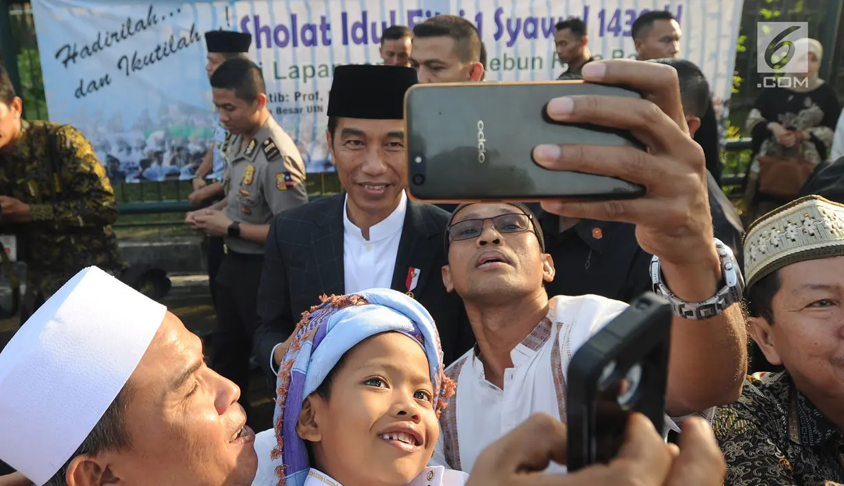 Seorang warga berselfie dengan Presiden Joko Widodo usai melaksanakan salat id Hari Raya Idul Fitri 1 Syawal 1439 H di Lapangan Astrid, Kebun Raya Bogor, Jumat (15/6). (Merdeka.com/Arie Basuki)
