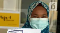 Tenaga kesehatan menunjukkan Kartu Vaksinasi COVID-19 saat vaksinasi di Puskesmas Jurang Mangu, Tangerang Selatan, Jumat (15/1/2021). Program vaksinasi COVID-19 tahap pertama kepada tenaga kesehatan mulai dilakukan di berbagai daerah di Indonesia. (Liputan6.com/Angga Yuniar)