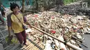 Warga melewati jembatan bambu di atas Sungai Kalibaru yang sudah menjadi tumpukan sampah di Kampung Bambu Kuning, Bojong Baru, Bogor (12/9). (Merdeka.com/Arie Basuki)