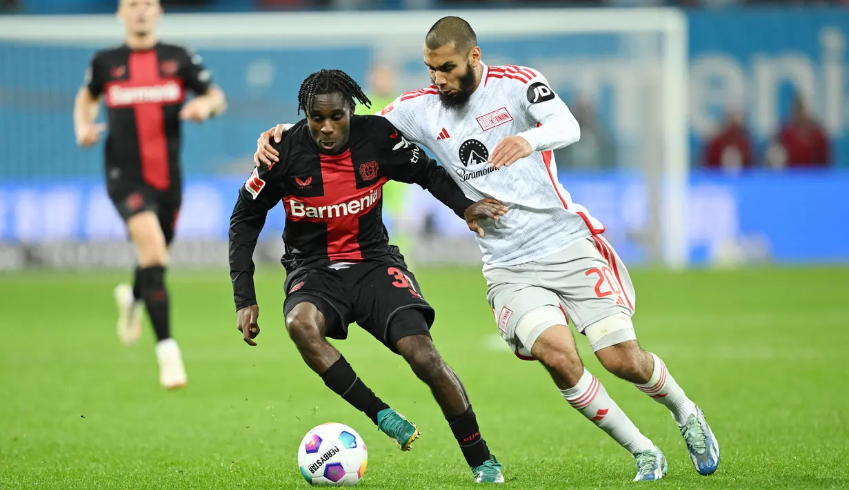 Pemain Bayer Leverkusen, Jeremie Frimpong, berebut bola dengan pemain Union Berlin, Aissa Laidouni, pada laga Bundesliga di Bay Arena, Minggu (12/11/2023). (AFP/Ina Fassbender)