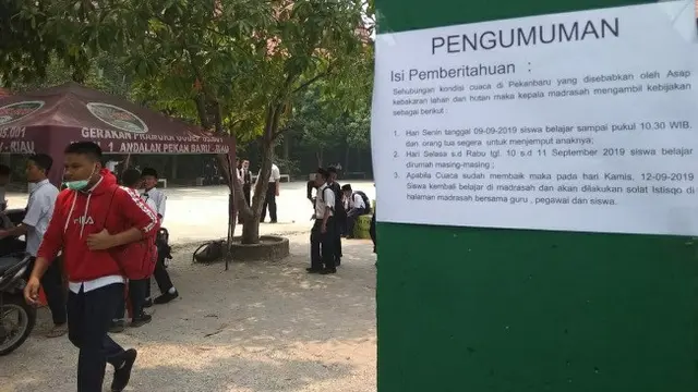 Sekolah di Pekanbaru memasang kertas pengumuman libur karena kabut asap hasil kebakaran lahan.