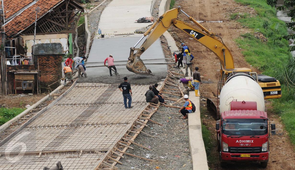 Pekerja dibantu alat berat menyelesaikan pembangunan jalan Inspeksi di kawasan kali Ciliwung Kalibata, Jakarta, Rabu (30/11). Pemprov DKI Jakarta membangun jalan inspeksi di seluruh sungai di Jakarta. (Liputan6.com/Gempur M Surya)