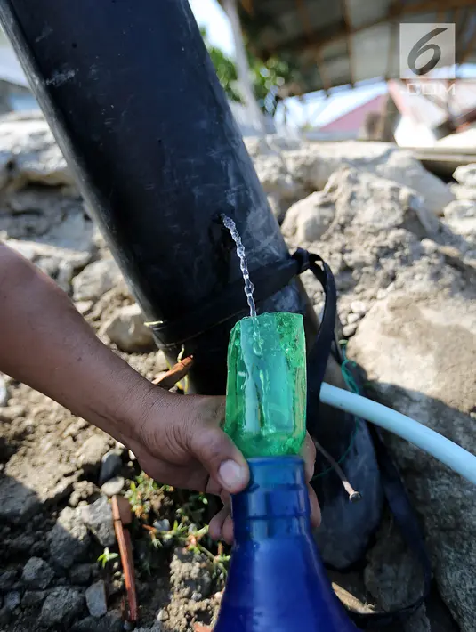 Warga memanfaatkan air bersih dari kebocoran pipa PDAM di Jalan Lagarutu, Palu Sulawesi Tengah, Rabu (3/10). Mereka mengisi air dari pipa PDAM menggunakan selang yang disalurkan ke dalam galon. (Liputan6.com/Fery Pradolo)