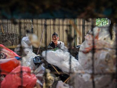 Seorang pekerja memilah sampah plastik yang dikumpulkan di sebuah depo dari 660 bank sampah di seluruh Surabaya, Jawa Timur pada 17 Juni 2025. (JUNI KRISWANTO/AFP)