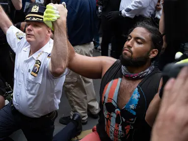 Kepala Departemen Kepolisian Kota New York, Terence Monahan berlutut bersama pengunjuk rasa dalam aksi protes kematian George Floyd, Senin (1/6/2020). Unjuk rasa besar melanda Amerika atas kematian pria kulit hitam yang tak bisa bernafas karena tercekik lutut polisi saat ditangkap. (AP/Craig Ruttle)