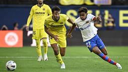 Pemain Barcelona, Lamine Yamal, berusaha melewati pemain Villarreal, Alfonso Pedraza, pada laga Liga Spanyol 2023/2024 di Stadion La Ceramica, Minggu (27/8/2023). Barca menang dengan skor 4-3. (AFP/Javier Soriano)