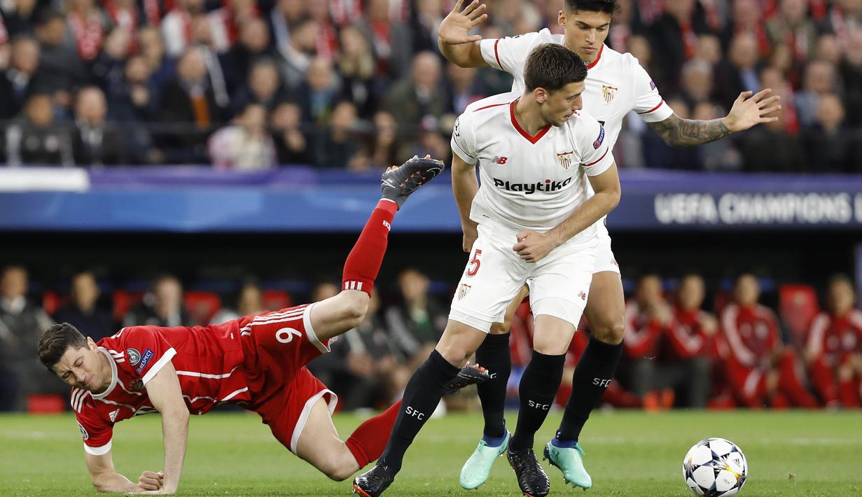 Pemain Bayern Munchen, Robert Lewandowski (kiri) jatuh saat berebut bola dengan pemain Sevilla pada leg pertama Liga Champions di Sanchez Pizjuan stadium, Seville, (3/4/2018) waktu setempat. Beyern menang 2-1. (AP/Miguel Morenatti)