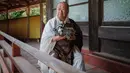 Pemuka agama kuil Kofukuji, Bungen Oi membawa robot peliharaan Sony AIBO seusai upacara pemakaman robot di Isumi, Jepang, Kamis (26/4). Robot-robot yang dimakamkan di kuil itu merupakan versi lawas dari robot peliharaan Sony AIBO. (AFP/Nicolas Datiche)