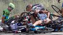 Seorang pebalap tampak tertindih sepedanya usai insiden kecelakaan yang melibatkan puluhan pebalap sepeda saat babak ketiga Tour de France dari Anvers ke Huy di Belgia, Senin (6/7/2015). (REUTERS/Eric Gaillard)