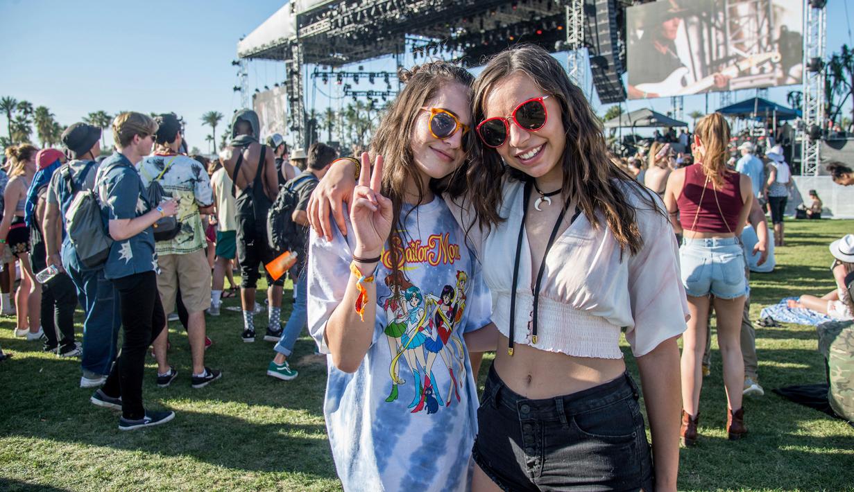 Dua wanita berpose sambil tersenyum saat menghadiri Coachella Music & Arts Festival di Empire Polo Club di Indio, California (15/4). Festival Coachella ini sudah ada sejak 1999. (Photo by Amy Harris/Invision/AP)