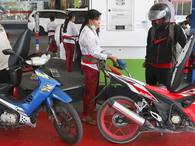 Petugas dengan pakaian adat mengisi bahan bakar minyak (BBM) untuk sepeda motor di SPBU, Bali, Rabu (10/10). Petugas SPBU mengenakan pakaian adat Bali untuk menyambut pertemuan tahunan IMF dan Bank Dunia. (Liputan6.com/Angga Yuniar)