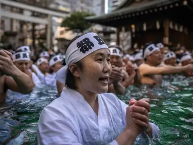 Penganut Shinto mandi dengan air dingin di Kuil Teppozu Inari, Tokyo, Jepang, 8 Januari 2023. Ritual Tahun Baru ini dilakukan untuk memurnikan jiwa dan raga. (Philip FONG/AFP)