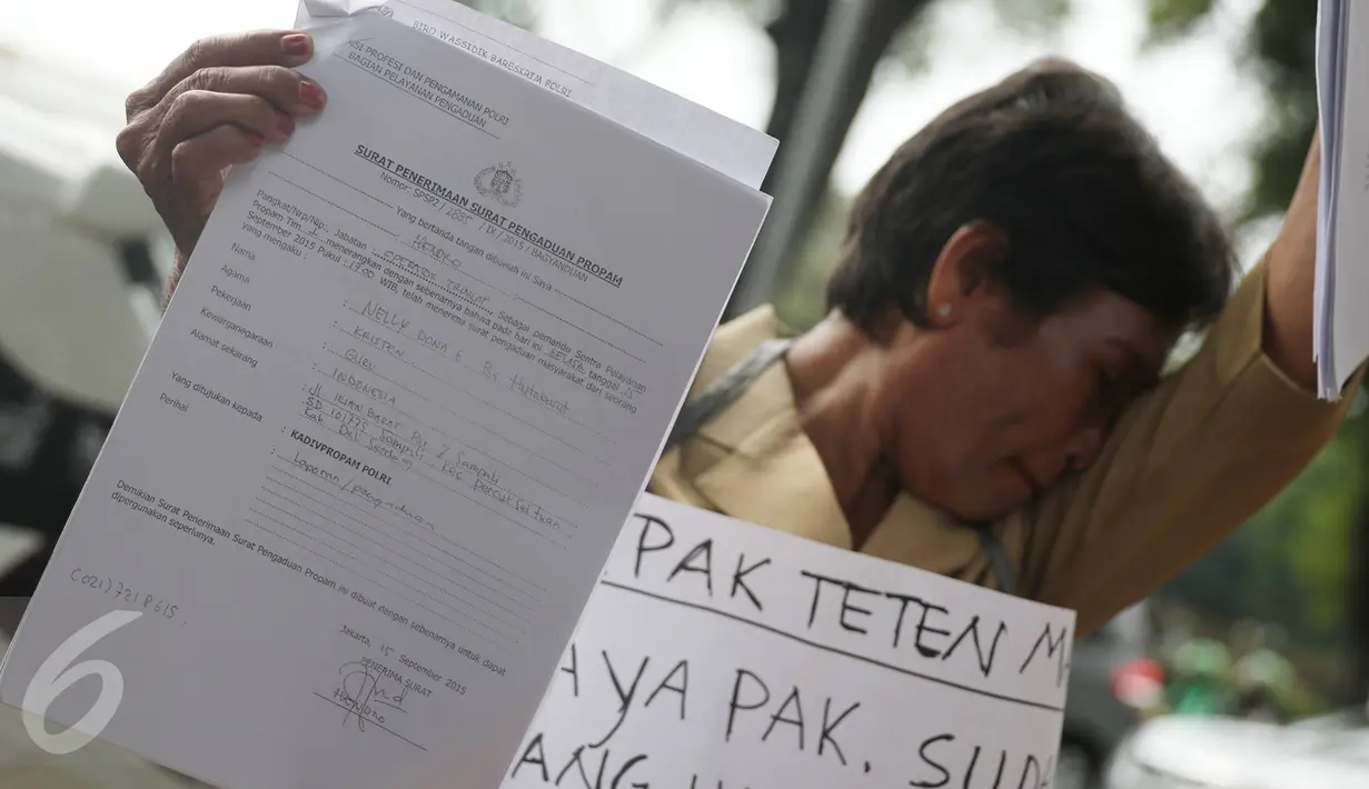 Nelly Hutabarat, guru asal Deli Serdang, menunjukkan surat pengaduan saat aksi diam di depan Istana Negara, Rabu (13/7). Nelly menuntut keadilan atas penutupan SDN 10-61-59 dan pembongkaran rumah dinasnya 2011 silam. (Liputan6.com/Immanuel Antonius)