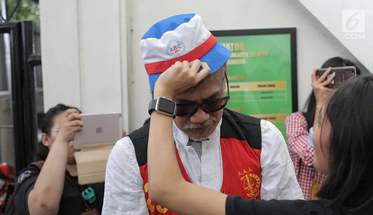 Putri terdakwa kasus penyalagunaan narkoba Tio Pakusadewo, Patricia memakaikan topi ke kepala ayahnya sebelum sidang lanjutan di PN Jakarta Selatan, Kamis (12/7). Sidang beragendakan pembacaan duplik atas replik dari JPU. (Liputan6.com/Faizal Fanani)