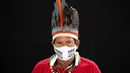 Pemimpin adat dari etnis Miranha Jose Augusto (48) mengenakan pakaian tradisional sukunya dan masker saat pandemi virus corona COVID-19 di Taman Bangsa Adat, Manaus, Brasil, Kamis (28/5/2020). Maskernya berbunyi dalam bahasa Portugis: “Kehidupan orang pribumi penting”. (AP Photo/Felipe Dana)