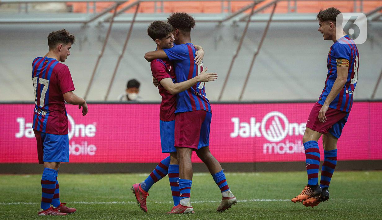 Pemain Barcelona U-18 Jan Molina Vilaseca (kedua kiri) berpelukan dengan Jorge Javier Espinal Díaz saat melawan Bali United U-18 pada pertandingan International Youth Championship (IYC) 2021 di Jakarta International Stadium (JIS), Jakarta, Minggu (17/4/2022). (Liputan6.com/Faizal Fanani)