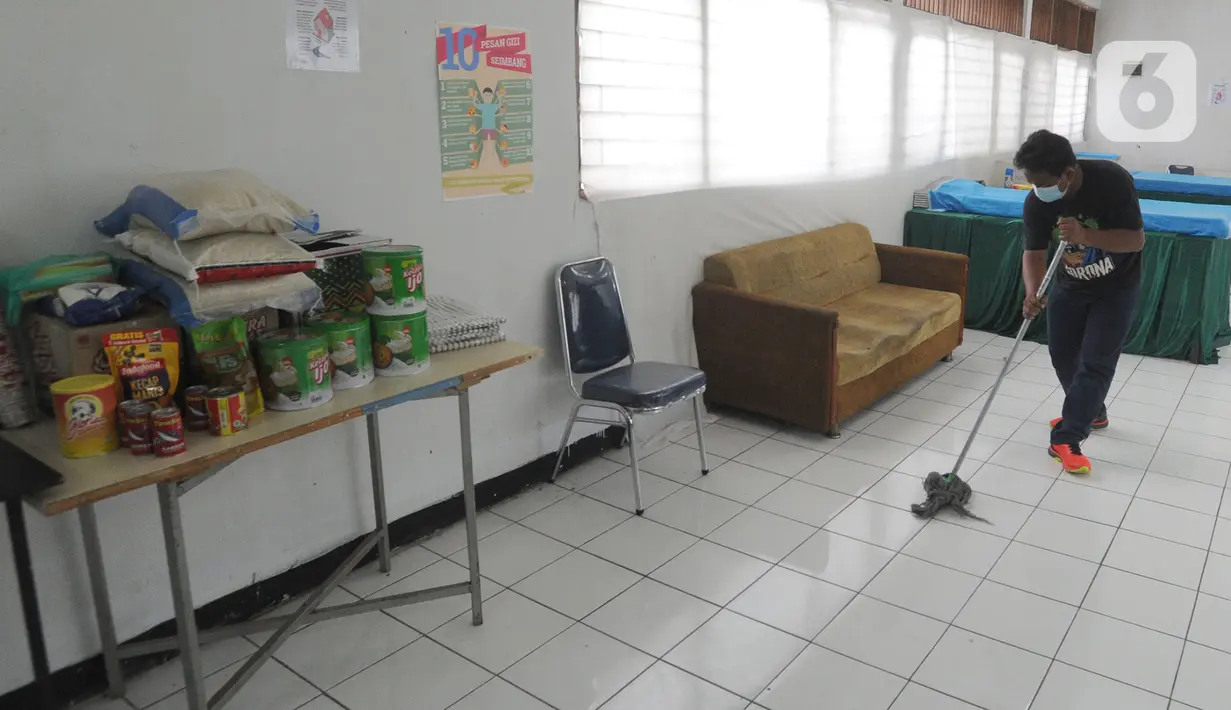 Petugas membersihkan ruangan dapur untuk isolasi mandiri di Gedung Sasana Krida Karang Taruna, Kelurahan Pondok Labu, Jakarta, Selasa (19/01/2020). Di tempat ini juga disediakan bahan makanan, alat memasak dan berbagai perlengkapan standar pasien Covid-19. (merdeka.com/Arie Basuki)