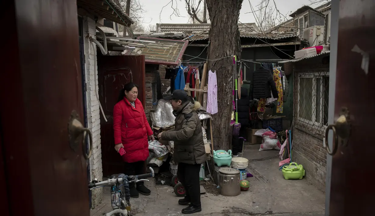 Seorang pria dan wanita berbicara di sebuah halaman di luar rumah mereka di daerah hutong di Beijing (26/2). Di Beijing, hutong adalah lorong-lorong yang dibentuk oleh garis siheyuan, tempat tinggal halaman tradisional. (AFP Photo/Nicolas Asfouri)