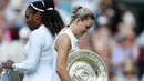 Petenis Jerman, Angelique Kerber (kanan) membawa trofi usai mengalahkan petenis AS, Serena Williams pada final tunggal putri kejuaraan Tenis Wimbledon 2018 di London, (14/7). Kerber menang atas Williams 6-3,6-3. (AP Photo/Nic Bothma)