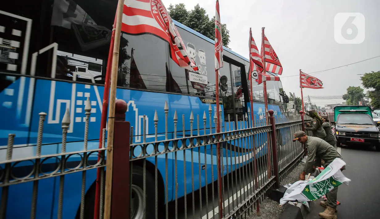 Satu per satu bendera partai politik ditertibkan oleh petugas Satpol PP. (Liputan6.com/Faizal Fanani)