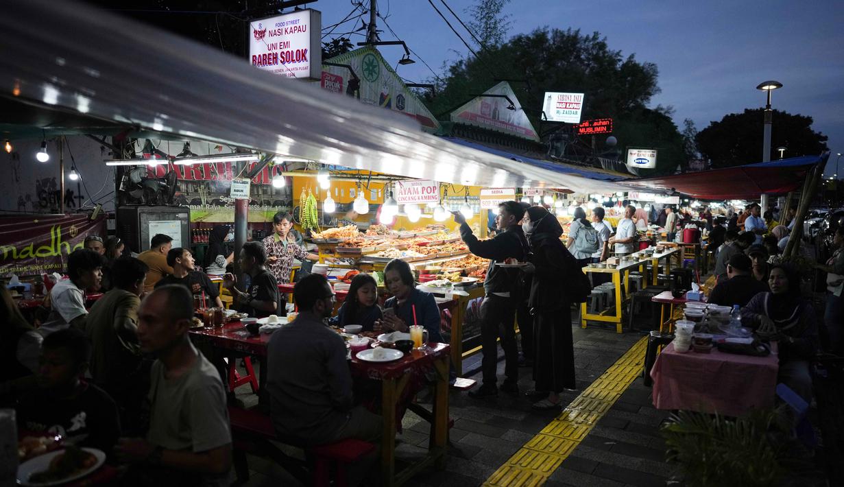 Meski sudah ada di kawasan Kramat Raya sejak tahun 1970-an, namun keberadaan sentra kuliner ini baru diresmikan Pemprov DKI Jakarta pada akhir Mei 2017 lalu. Tampak dalam foto, warga membeli makanan untuk berbuka puasa pada hari kedua bulan suci Ramadan 1447 Hijriah, di sebuah warung makan, Jakarta, Jumat 20 Februari 2026. (AP Photo/Dita Alangkara)