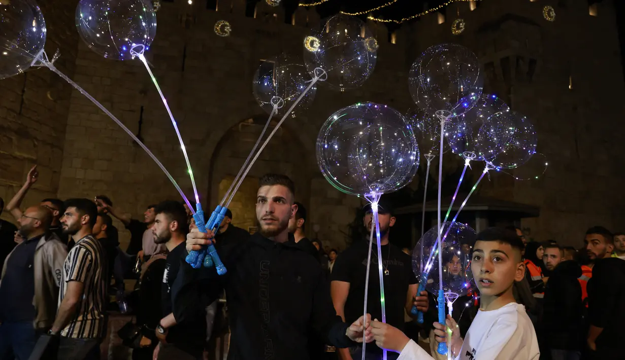 Warga Palestina menjual balon pada hari pertama bulan suci Ramadhan di luar gerbang Damaskus di Kota Tua Yerusalem, 2 April 2022. Ramadan adalah bulan suci umat Islam yang dirayakan dengan cara melaksanakan puasa selama satu bulan penuh. (Menahem KAHANA / AFP)