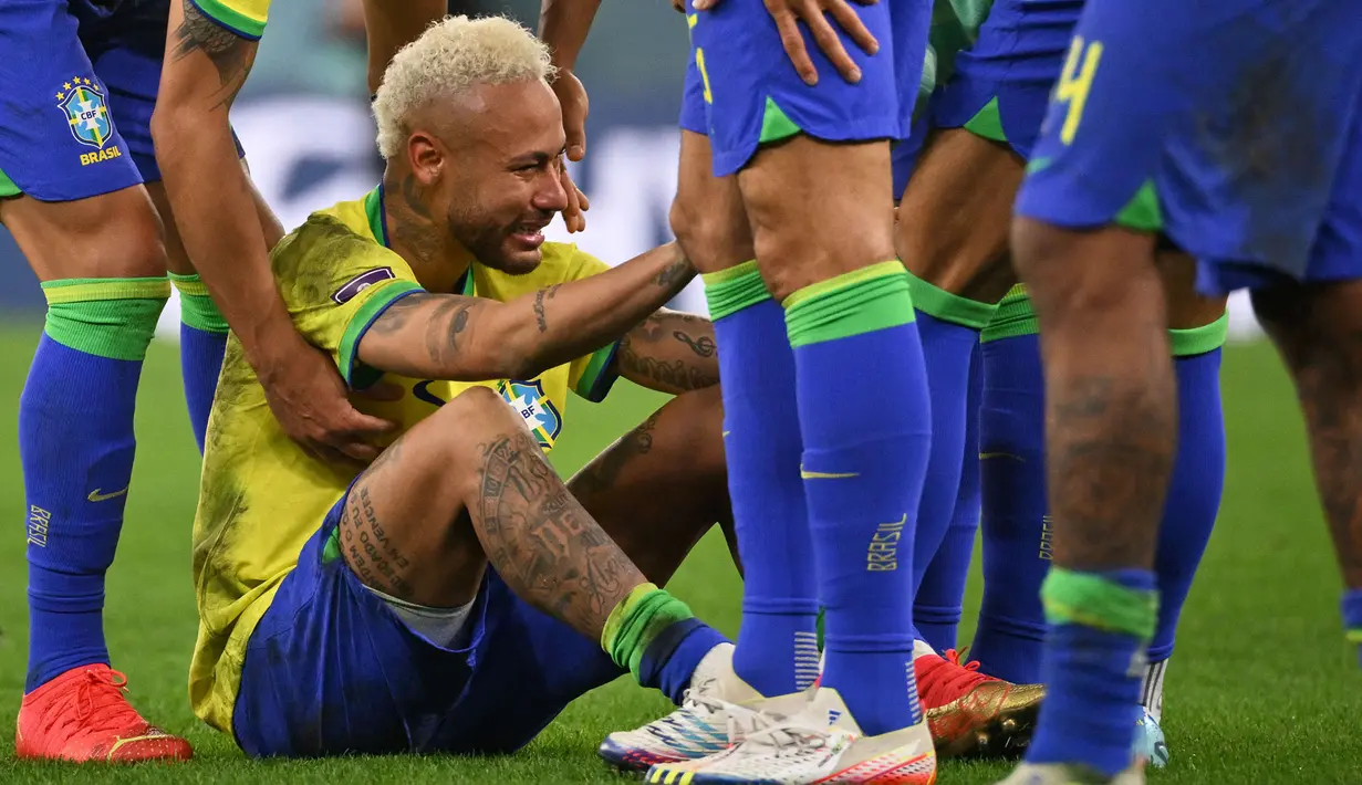 Pemain Brasil, Neymar dihibur oleh rekan-rekannnya setelah tim mereka kalah dari Kroasia saat laga perempat final Piala Dunia Qatar 2022 yang berlangsung di Education City Stadium, Al-Rayyan, Jumat (09/12/2022) waktu setempat. Brasil kalah 2-4 dari Kroasia saat babak adu penalti. (AFP/Adrian Dennis)