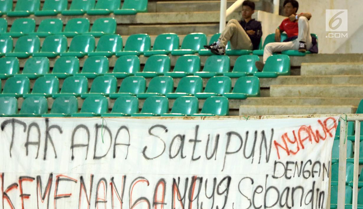 Suporter menyaksikan laga Indonesia U-19 melawan China U-19 pada PSSI 88th U-19 International Tournament di Stadion Pakansari, Selasa (25/9). Suporter membentangkan spanduk keprihatinan atas aksi kekerasan yang terjadi. (Liputan6.com/Helmi Fithriansyah)