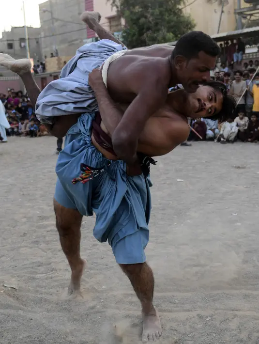 Pegulat bertarung selama turnamen gulat tradisional Sindhi Malakhra di kota pelabuhan Karachi, Pakistan pada Minggu (13/12/2020). Gulat kuno yang dimulai sejak 5.000 tahun lalu ini salah satu olahraga favorit di kalangan pria. (Photo by Asif HASSAN / AFP)