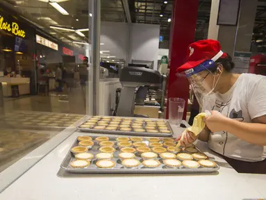 Seorang staf toko kue yang mengenakan pelindung wajah membuat kue tart telur (egg tart) di Square One Shopping Center di Mississauga, Ontario, Kanada  (9/10/2020). Tingkat pengangguran di Kanada pada September turun menjadi 9 persen dari 10,2 persen pada Agustus. (Xinhua/Zou Zheng)