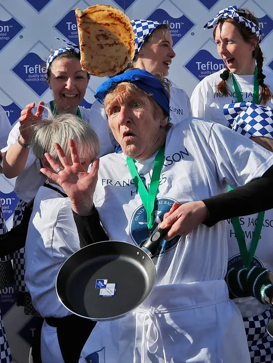 Peserta berkumpul setelah menyelesaikan lomba lari dengan membawa pancake dalam lomba tahunan Pancake Trans-Atlantic di Olney, Buckinghamshire, Inggris, Selasa (5/3). Lomba pada Hari Pancake ini diadakan satu hari menjelang Rabu Abu. (AP/Frank Augstein)