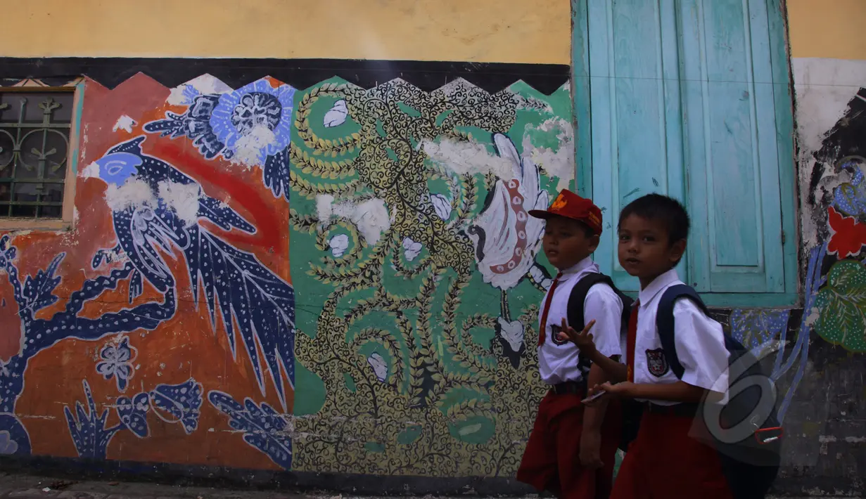 Pelajar melintasi tembok bergambar burung merak yang merupakan khas batik Sidoarjo di Kampung batik, Sidoarjo, Senin (31/03/2015). Produksi batik Kota Sidoarjo ini sejak tahun 1960-an hingga saat ini masih tetap bertahan. (Liputan6.com/Andrian M Tunay)