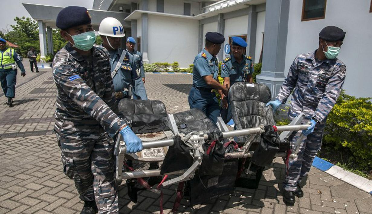 Petugas membawa puing AirAsia QZ8501 berupa bangku yang sudah rusak parah, Bandara Juanda, Rabu (7/1/2015). (AFP Photo/Juni Kriswanto)