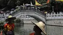 Warga berkerumun di jembatan untuk menunggu perahu naga di sepanjang kanal di kawasan bersejarah Teluk Lychee di Guangzhou di Provinsi Guangdong, China selatan, Jumat, 3 Juni 2022. Perlombaan perahu naga kembali digelar di beberapa bagian China untuk pertama kalinya sejak merebaknya pandemi pada akhir 2019, saat pembatasan dicabut bersama dengan penurunan besar  kasus COVID-19. (AP Photo/Caroline Chen)