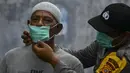Petugas polisi memasangkan masker kepada warga saat kabut asap tebal menyelimuti wilayah Banda Aceh (25/9/2019). Kebakaran hutan Indonesia menyebabkan hampir 10 juta anak dalam risiko pencemaran udara. (AFP Photo/Chaideer Mahyuddin)
