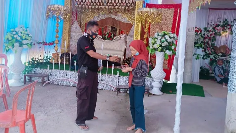 Personel Polsek Tenayan Raya berbincang dengan calon pengantin perempuan yang calon suaminya terkonfirmasi Covid-19.