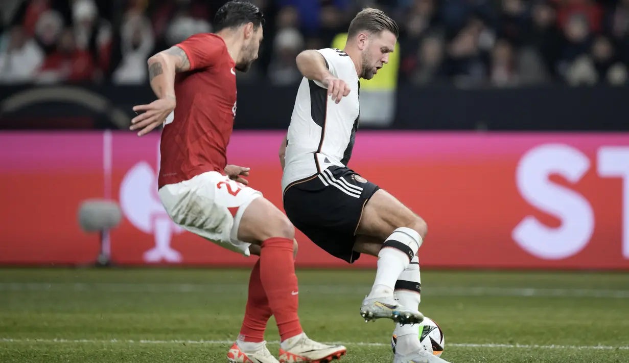 <p>Penyerang Jerman Niclas Fuellkrug berebut bola dengan bek Turki Kaan Ayhan dalam pertandingan international friendly di Olympiastadion, Berlin, Minggu (19/11/2023) dini hari WIB. (AP Photo/Markus Schreiber)</p>