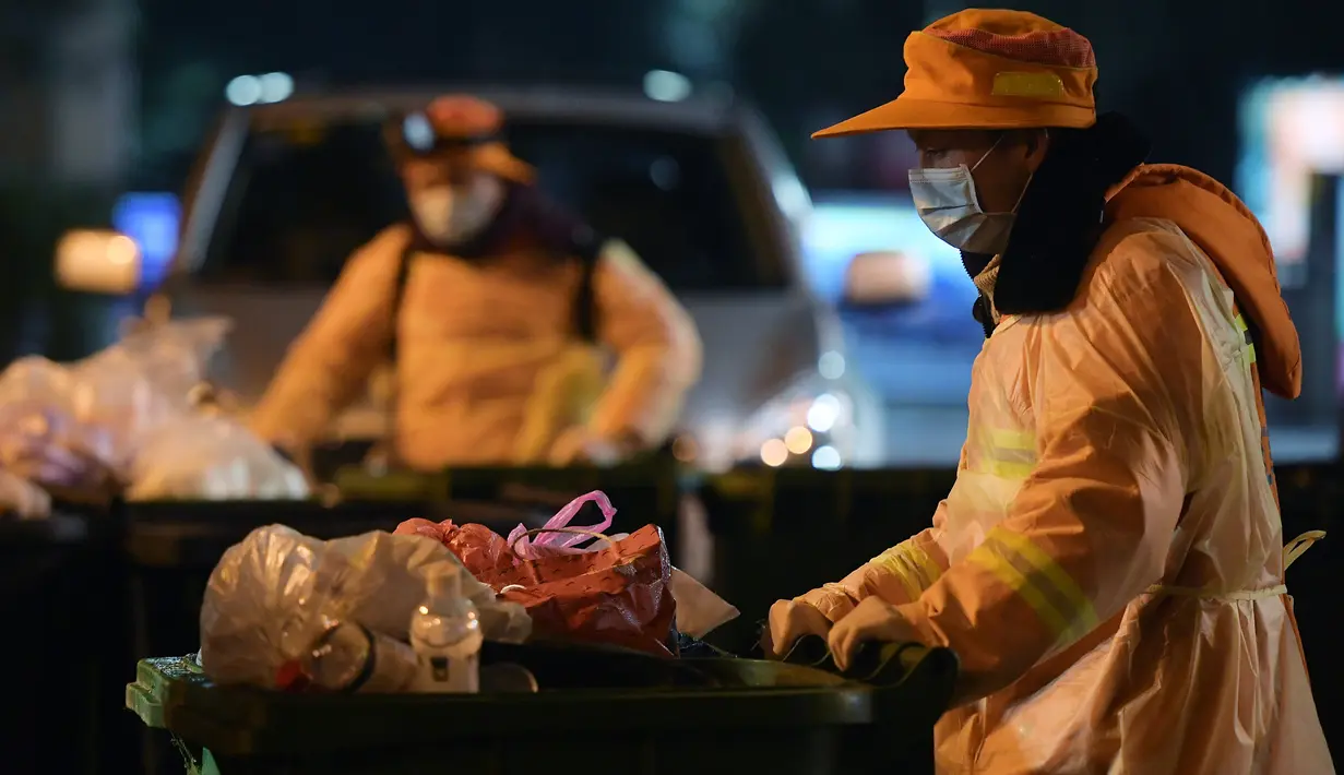 Pekerja sanitasi yang berjaga di pos mereka membersihkan sampah di sebuah daerah permukiman pada malam hari di Wuhan, Provinsi Hubei, China tengah, pada 1 Februari 2020. (Xinhua/Li He)