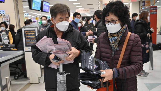 Orang-orang membeli masker di toko ritel di kota tenggara Daegu, Selasa (25/2/2020). Otoritas Korea Selatan (Korsel) melaporkan 60 kasus baru Virus Corona COVID-19di negeri itu pada hari ini, Selasa (25/2), sehingga kini total 893 orang terinfeksi virus tersebut. (Jung Yeon-je / AFP)