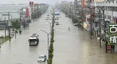 Orang-orang dan kendaraan menyeberangi air di sepanjang jalan yang tergenang banjir akibat Topan Gaemi di Kaohsiung, Taiwan pada tanggal 25 Juli 2024. ((Johnson LIU/AFP)