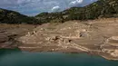Foto ini menunjukkan sisa-sisa rumah yang muncul kembali ketika permukaan danau buatan Mornos menurun akibat kekeringan, di desa Kallio, sekitar 240 km barat laut Athena, Yunani pada 3 November 2025. , ketika air surut, sisa-sisa desa, termasuk reruntuhan rumah, sekolah, dan bahkan lantai pertama dari beberapa bangunan, menjadi terlihat kembali. (Angelos TZORTZINIS/AFP)