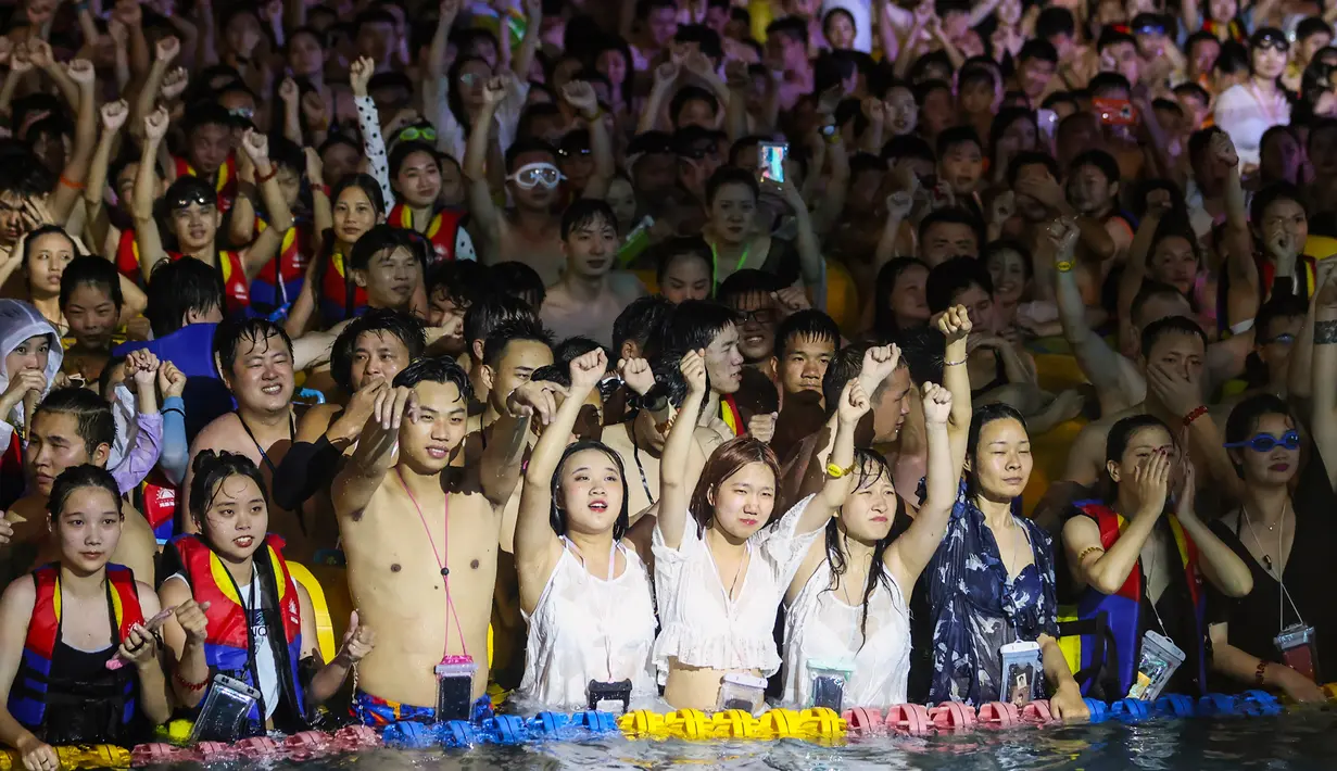 Orang-orang menonton pertunjukan musik sambil bermain air di sebuah taman air di Wuhan, provinsi Hubei, China pada 15 Agustus 2020. Menurut media lokal, pengelola taman air itu membatasi pengunjung hanya setengah dari kapasitas, serta menawarkan potongan harga bagi para perempuan. (STR/AFP)