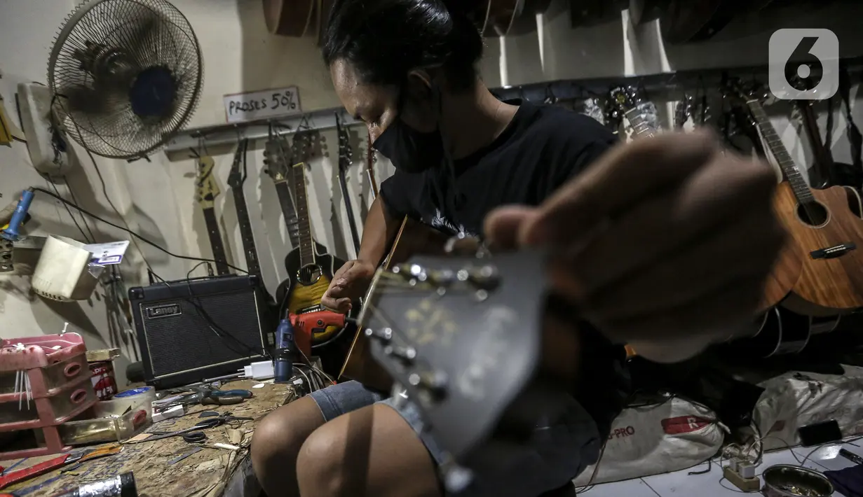 Harry saat mereparasi gitar klasik menjadi gitar listrik di toko kawasan Kedoya, Jakarta Barat, Selasa (9/2/2021). Toko bernama RMG ini merupakan toko servis dan reparasi gitar dengan berbagai merek. (Liputan6.com/Johan Tallo)